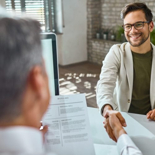 Happy male candidate greeting a member of human resource team on a job interview in the office.